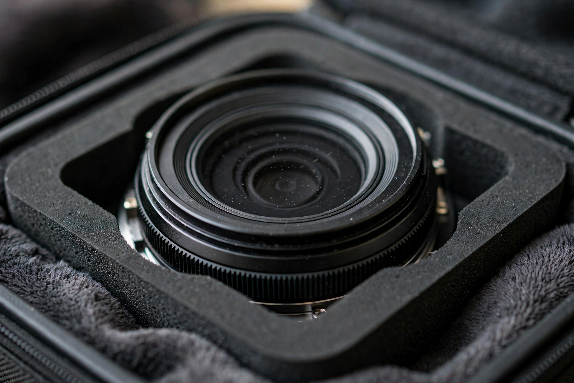 Macro of camera lens seated in precision die-cut foam cavity with microfiber lining